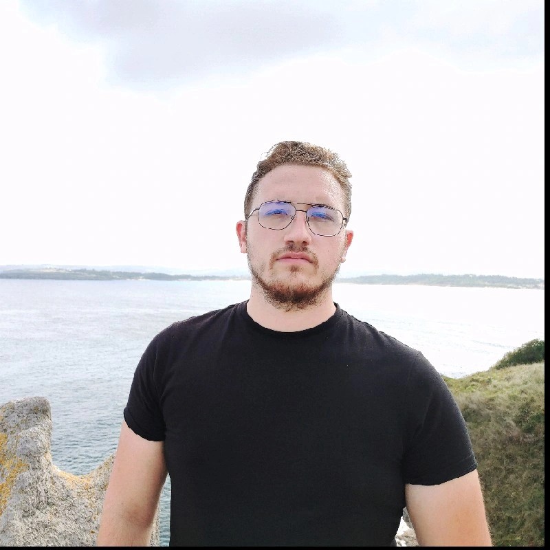 Retrato de profesional con gafas y camiseta negra frente al mar