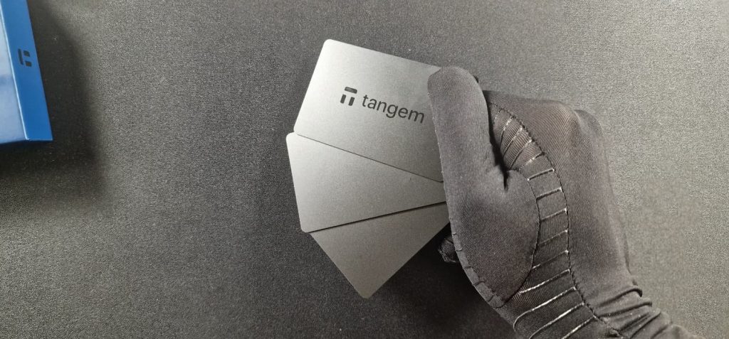 Tarjetas de privacidad Tangem Wallet en mano con guante, hardware wallet NFC