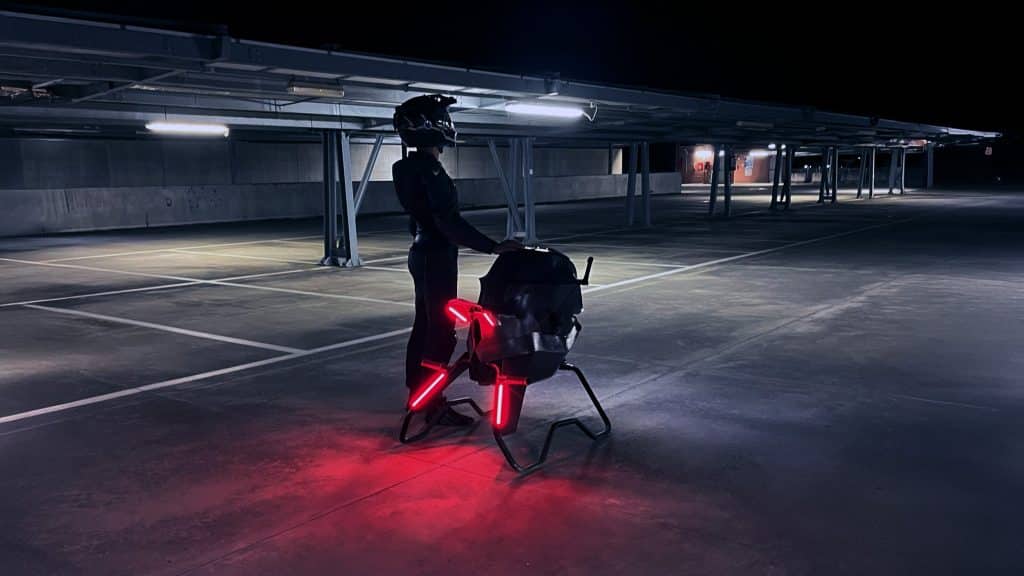 Volonaut Airbike hoverbike en aparcamiento nocturno, piloto con casco y luces rojas, movilidad aérea personal